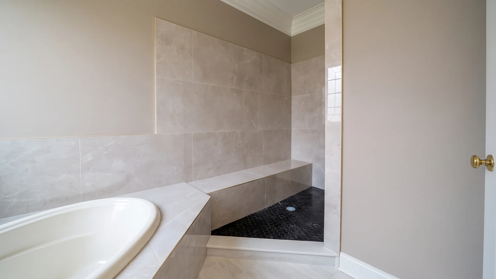 Large-format tile walk-in shower with a built-in bench and dark mosaic floor