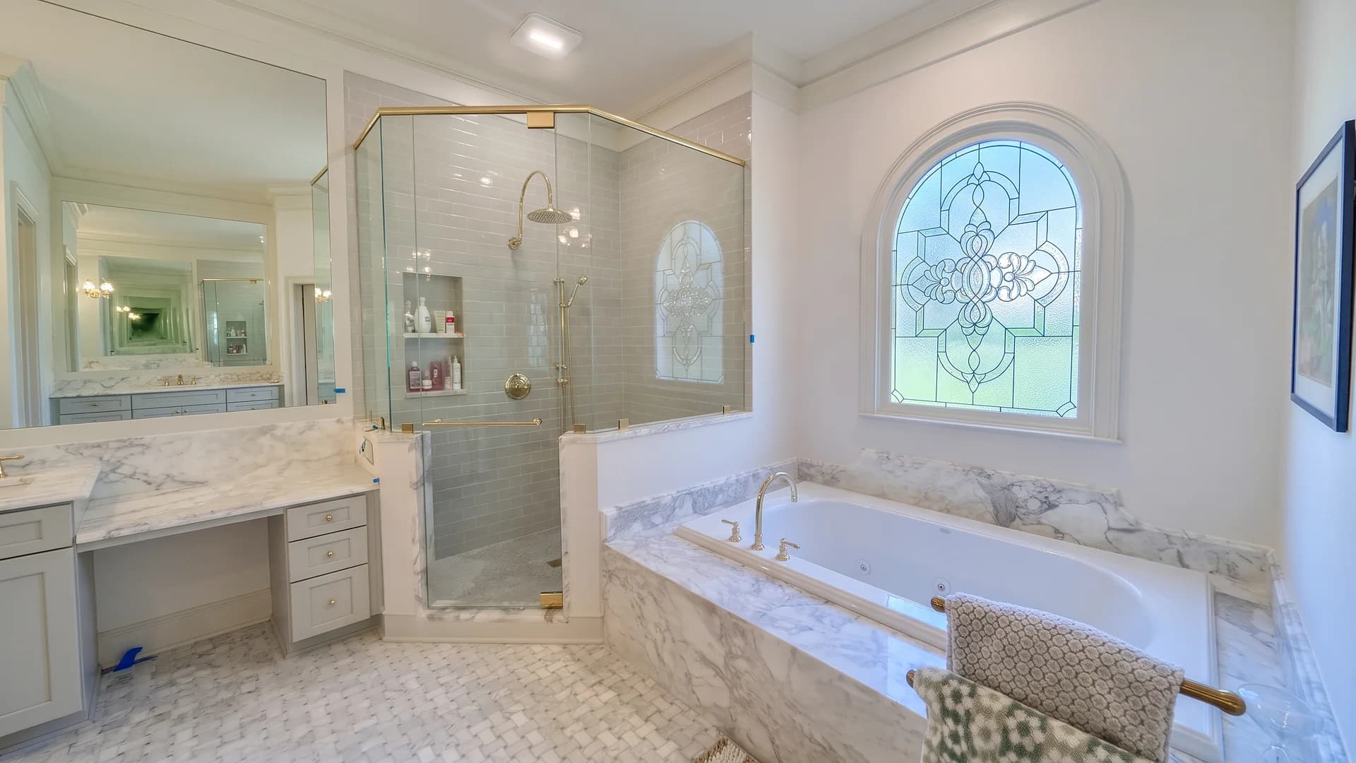 Bathroom with a marble-look tub deck, glass shower, and mosaic floor