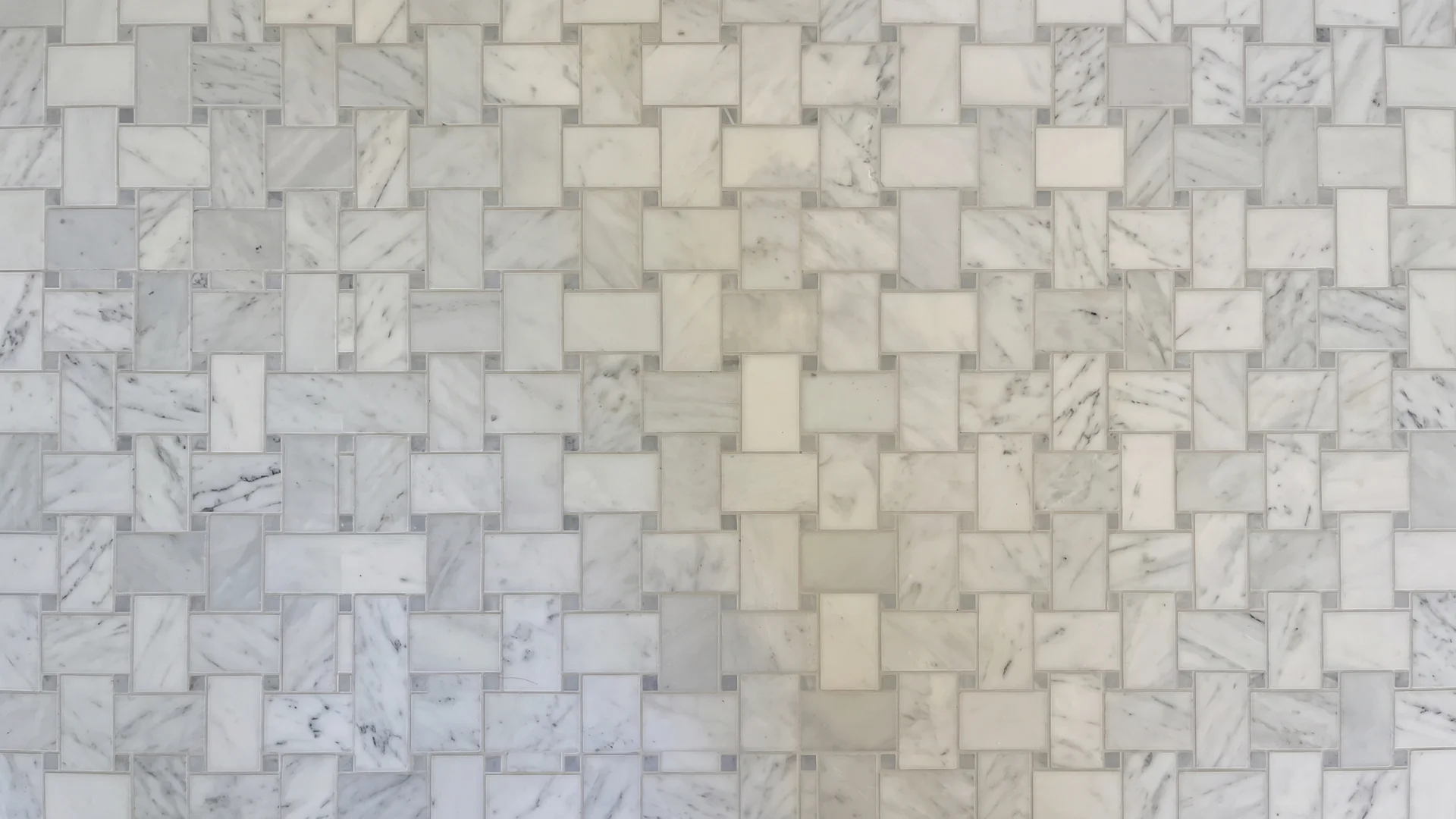 Close-up of a marble-look basketweave mosaic floor with clean, even grout lines