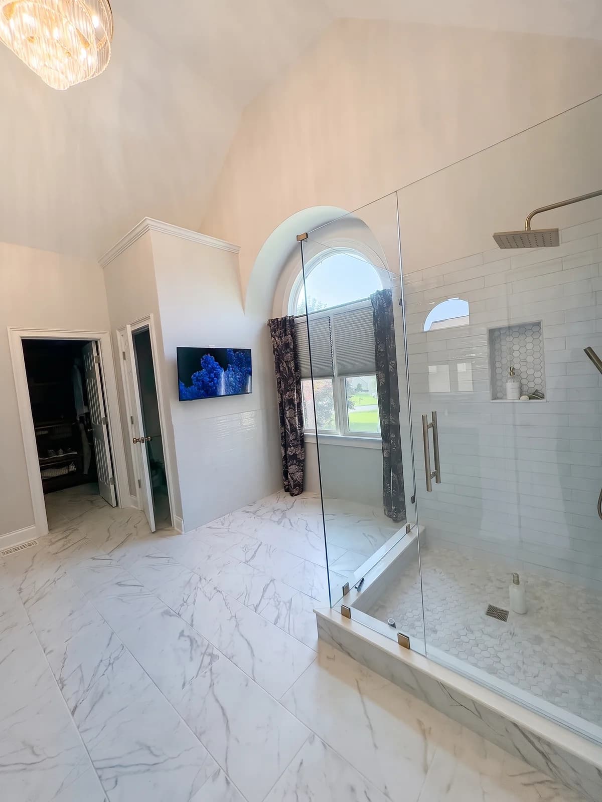 Master bathroom with marble-look porcelain floor tile and a frameless glass shower with white subway tile