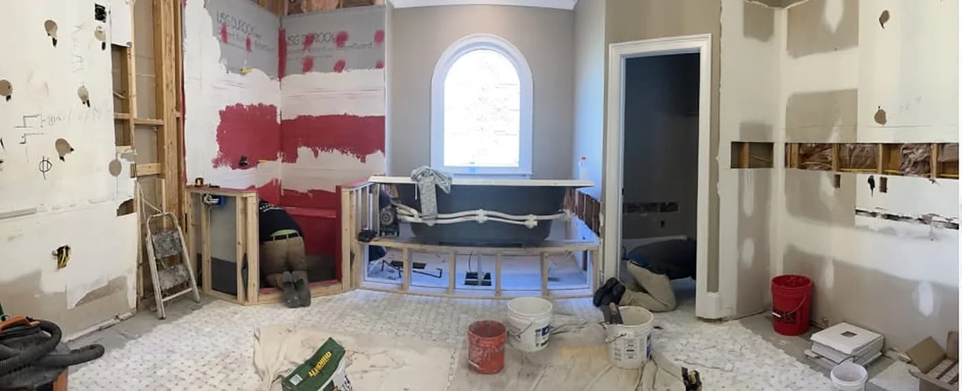 Master bathroom during demolition, with open studs, backer board, and the tub deck being framed
