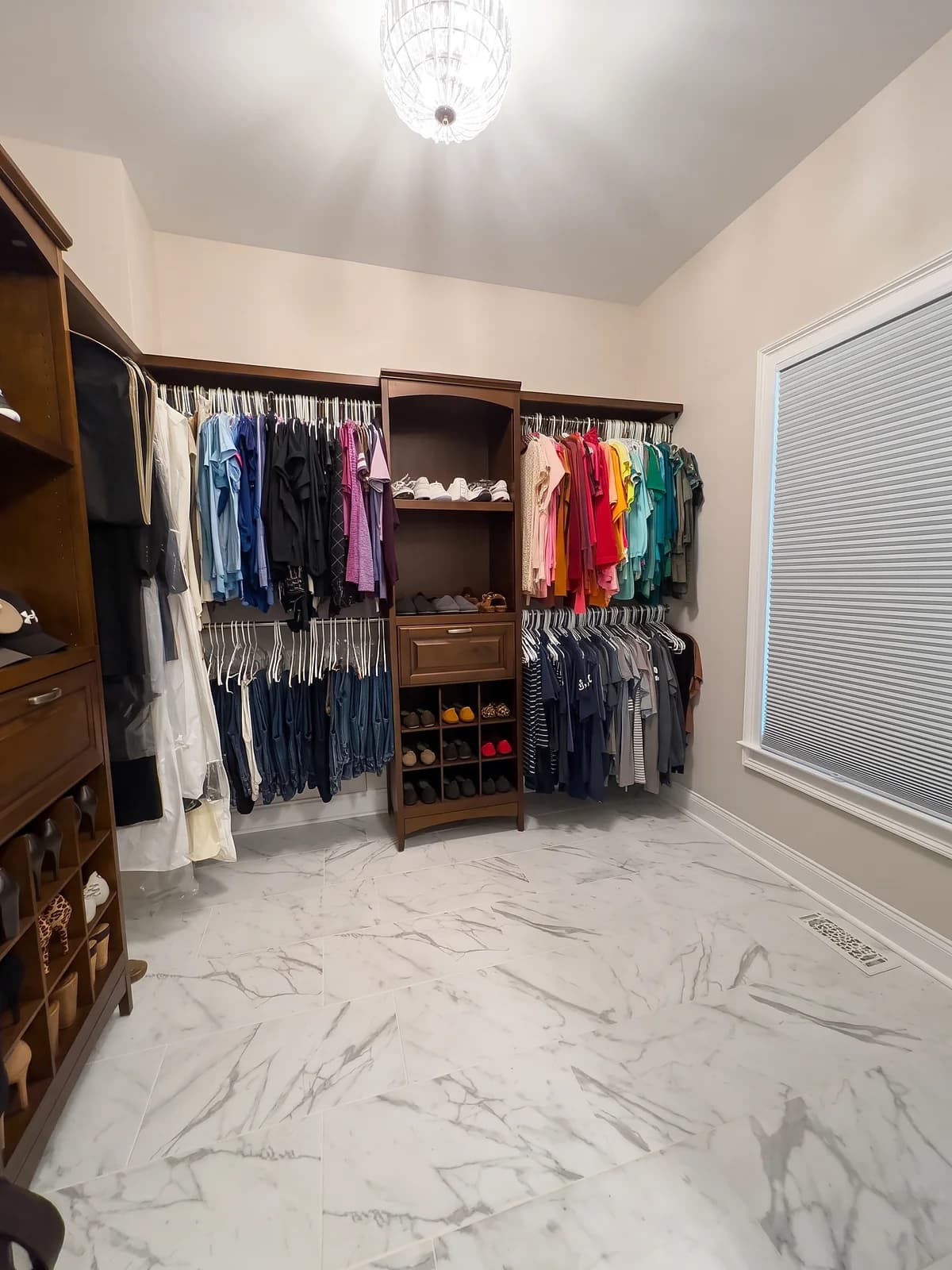 Second view of the walk-in closet with marble-look porcelain floor tile and wood closet shelving