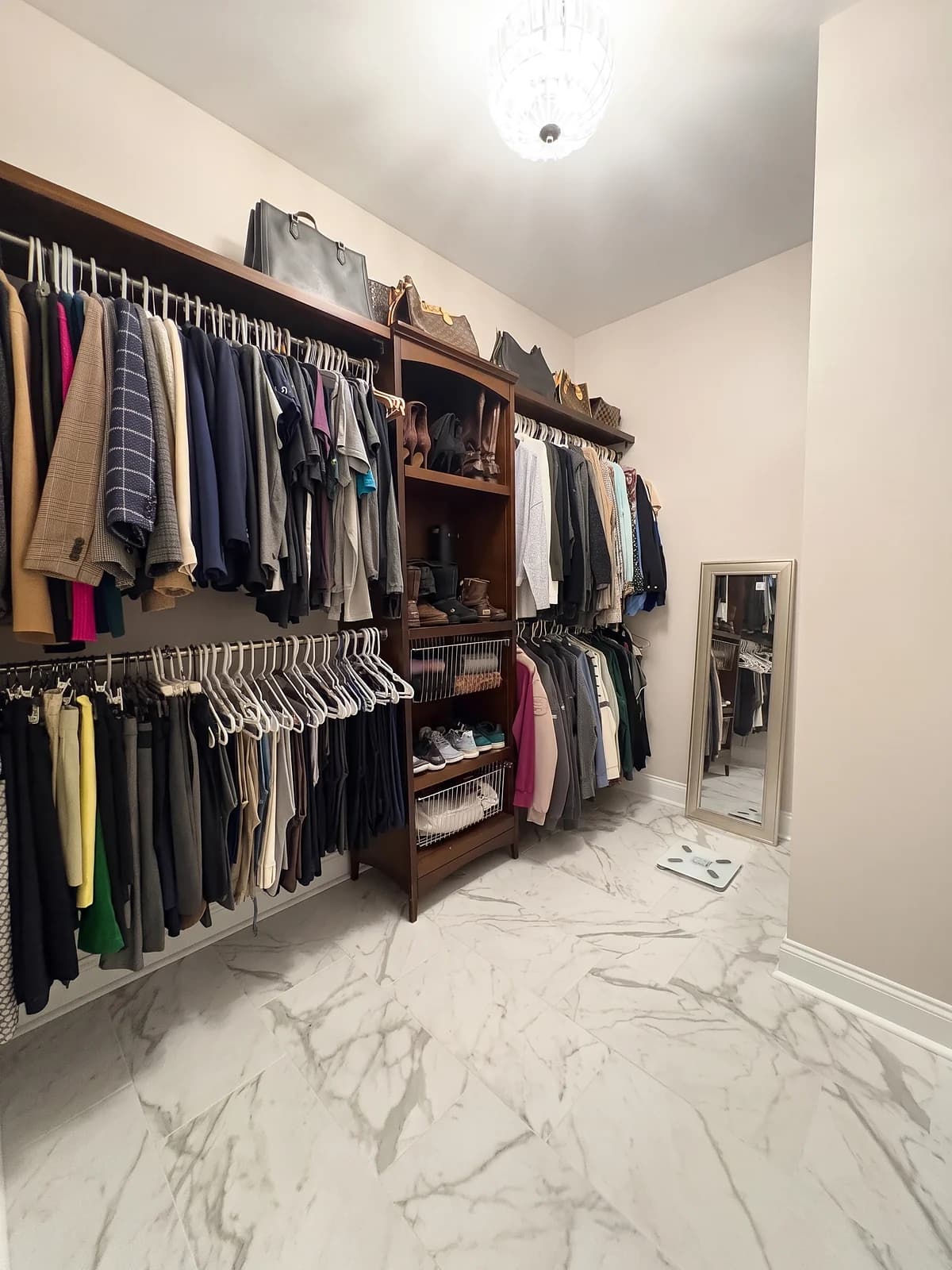 Walk-in closet with marble-look porcelain floor tile continuing from the master bathroom